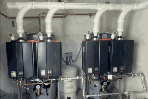 Four wall-mounted boilers with white vent pipes and copper plumbing