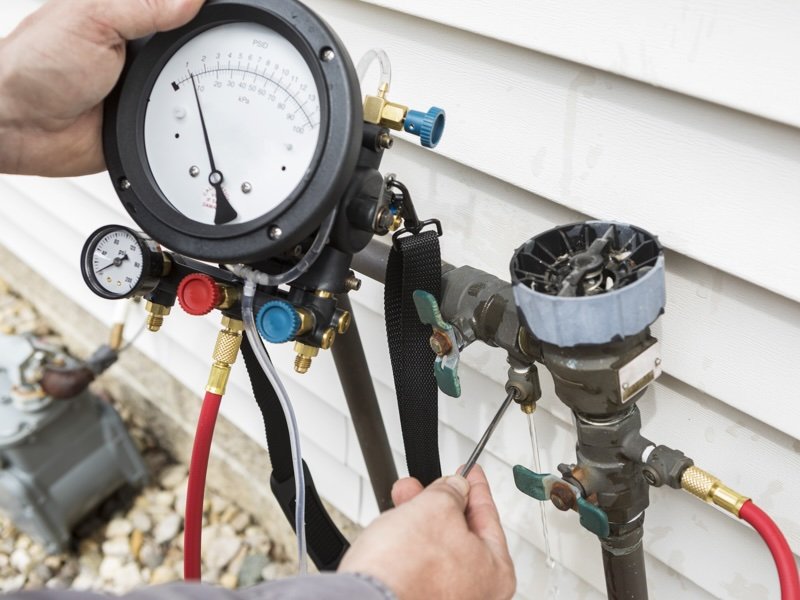Technician performing water pressure testing on an outdoor plumbing system in Naperville, IL 