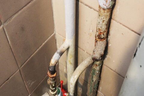 Corroded and rusty water pipes inside an apartment building