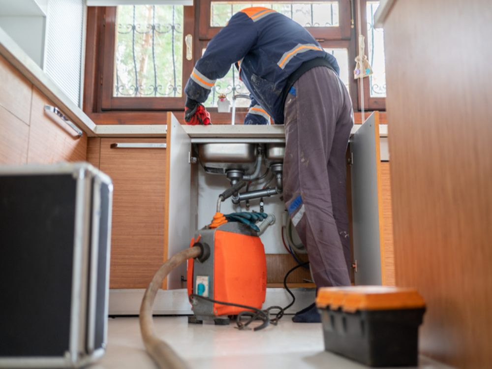 Plumber unclogging a blocked kitchen sink drain